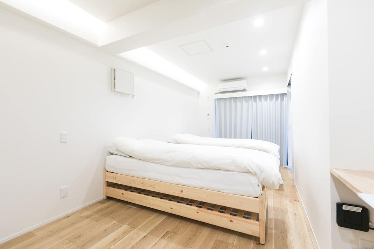 Une chambre à coucher moderne avec un lit en bois, des murs blancs et une lucarne.