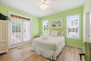 A bedroom with a bed, a ceiling fan, and a window with a view of a bridge.