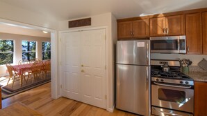 A kitchen with wooden cabinets, stainless steel appliances, and a dining area with a table and chairs.