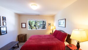 A bedroom with a bed, a bench, a window, and a lamp.