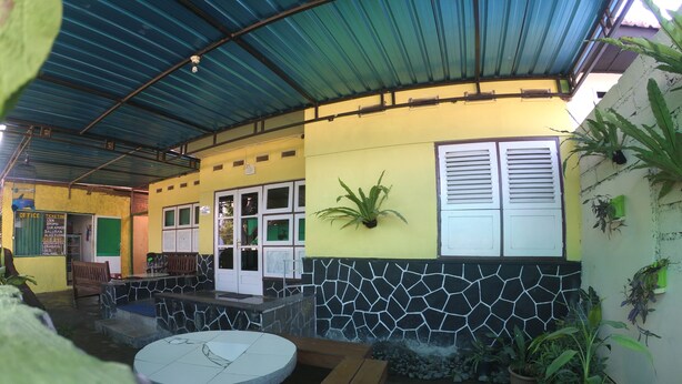 A covered outdoor area with a seating area, a small water feature, and potted plants. - Olivia Homestay (Banyuwangi)
