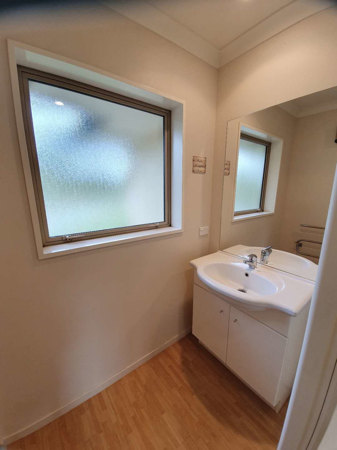 Une petite salle de bain avec une fenêtre, un lavabo et un miroir.