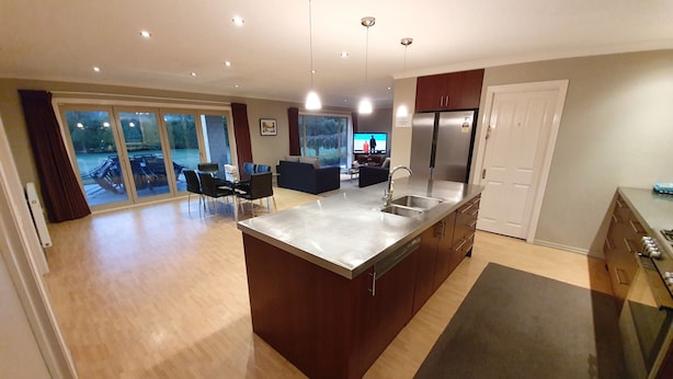 Una cocina moderna con una isla central, electrodomésticos de acero inoxidable y un comedor con vistas.