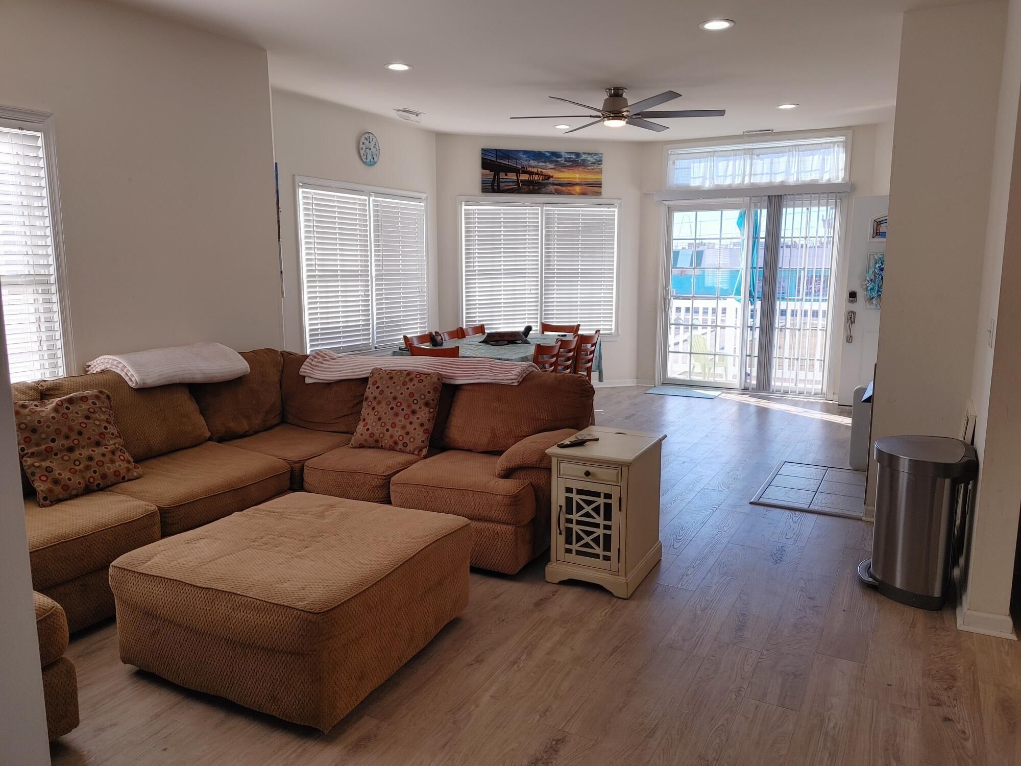 A spacious living room with a sectional sofa, a small table, and a ceiling fan.