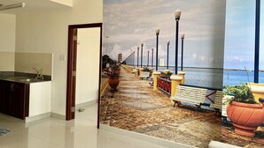 Ein Flur mit einem Wandbild einer Seepromenade, einer Küchenzeile und Blick aufs Meer.