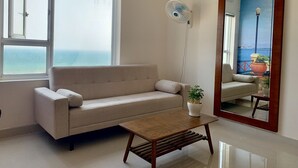 Ein modernes Wohnzimmer mit einer Couch, einem Couchtisch und einem großen Spiegel, der eine schöne Aussicht widerspiegelt.