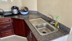 Eine Küche mit Granitabdeckung, Spüle aus Edelstahl, Holzschränken und einem Wasserkocher.