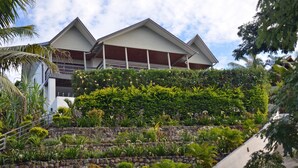 A modern building with a landscaped garden in front, featuring a stone retaining wall and various plants.
