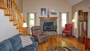 A spacious living room with a fireplace, wooden staircase, and a large mirror. - Willow Tree Lodge-Easy access - Secluded - Grill (Bryson City)