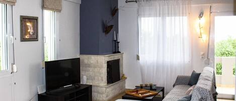 A living room with a flat-screen TV, a fireplace, a sofa, and a dining table.