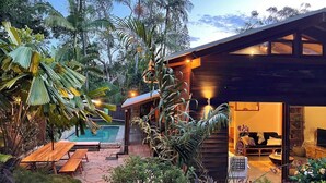 A modern house with a pool, wooden deck, and lush tropical vegetation. - Beach Jungle: Pet-Friendly Hot Tub, Firepit & Pool in Beachside Hideaway (Byron Bay)