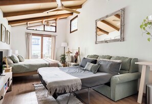 Une pièce confortable avec un lit, un canapé, un bureau et un miroir.