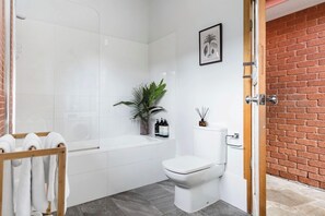Une salle de bain moderne avec une douche à l’italienne en verre, des toilettes blanches et une baignoire.