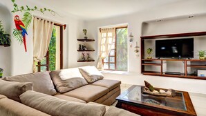 Una sala de estar con sofá, mesa de centro, televisor y puerta corrediza de vidrio que da a un balcón.