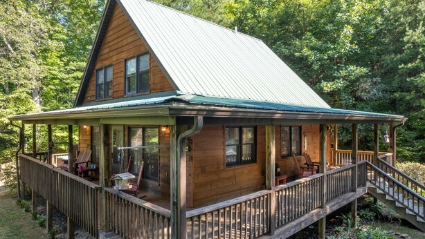 Une cabane en bois dotée d’un porche couvert, d’un escalier et d’une terrasse.