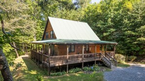 Une cabane dotée d’un porche couvert, d’un toit en pente et d’une allée gravillonnée.