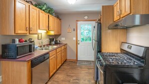 Une cuisine de taille réduite, dotée de meubles en bois, d’un four à micro-ondes, d’une cuisinière et d’un réfrigérateur.