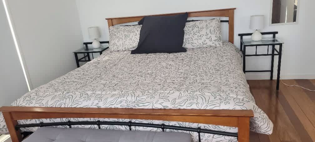 A bed with a patterned bedspread, two bedside tables with lamps, and a wooden headboard.
