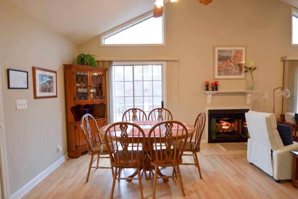 A dining area with a round table and chairs, a fireplace, and a window with a view.