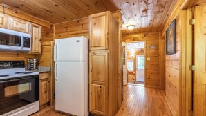 A wooden-paneled kitchen with a stove, microwave, and refrigerator. - Deep Creek Cottage-Creek side- close to the Polar Express (Bryson City)
