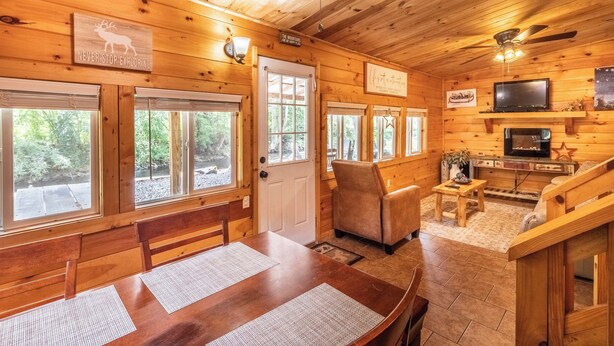 A wooden cabin interior with a dining area, a television, and a fireplace. - Deep Creek Cottage-Creek side- close to the Polar Express (Bryson City)