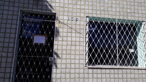 Ein Gebäude mit einer beschrifteten Tür und einem Fenster, beides mit Metallgittern gesichert.