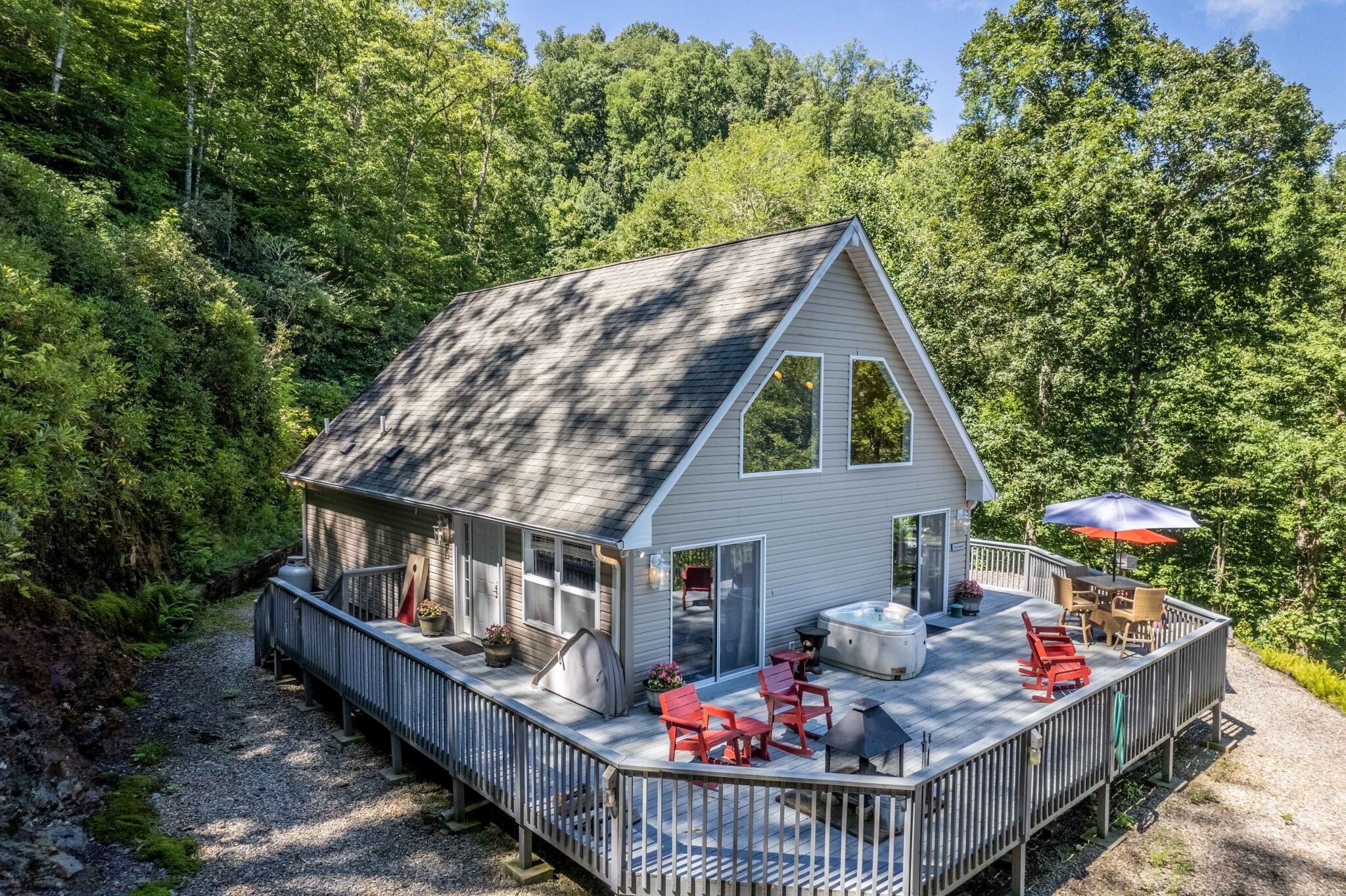 A cabin with a deck, outdoor seating, and a hot tub.