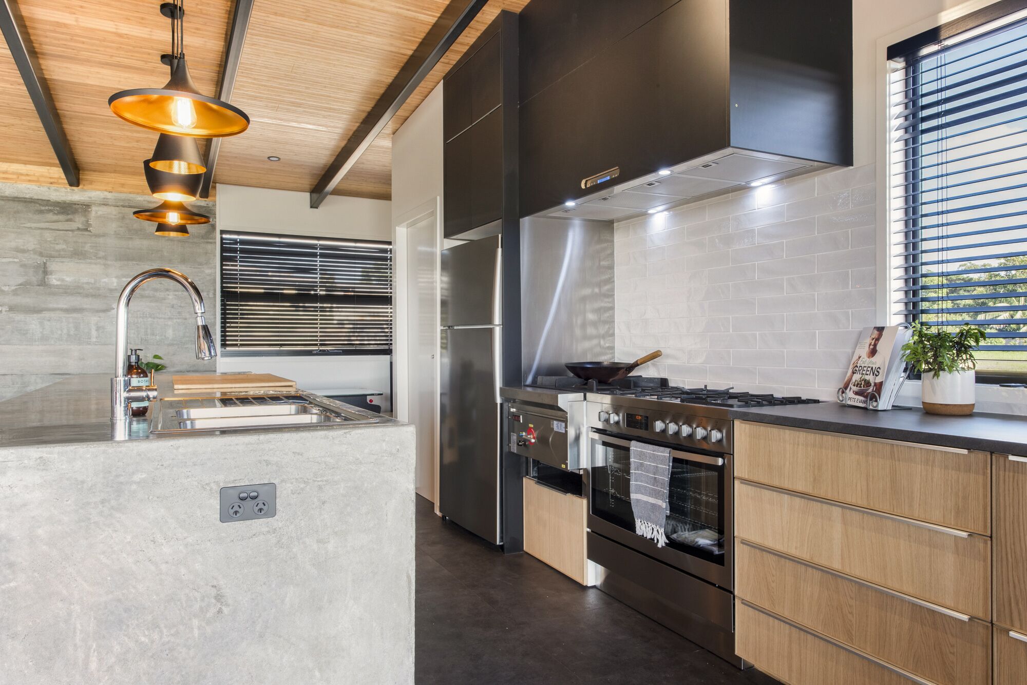 A modern kitchen with a built-in oven, a stainless steel range, and a wooden island with a sink.