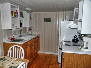 A compact kitchen with a sink, stove, and a sign indicating breakfast service. - Cozy Cabin on the Creek-Creek side- Secluded - Charcoal Grill (Bryson City)