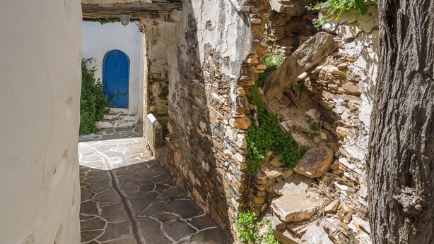 A narrow stone pathway leading to a building with a blue door and a window. - Marouso Villa Paros (Paros)
