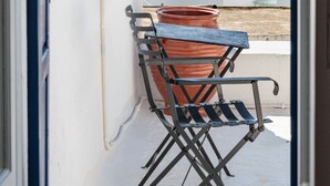 A balcony with a metal folding chair and a large terracotta pot. - Marouso Villa Paros (Paros)
