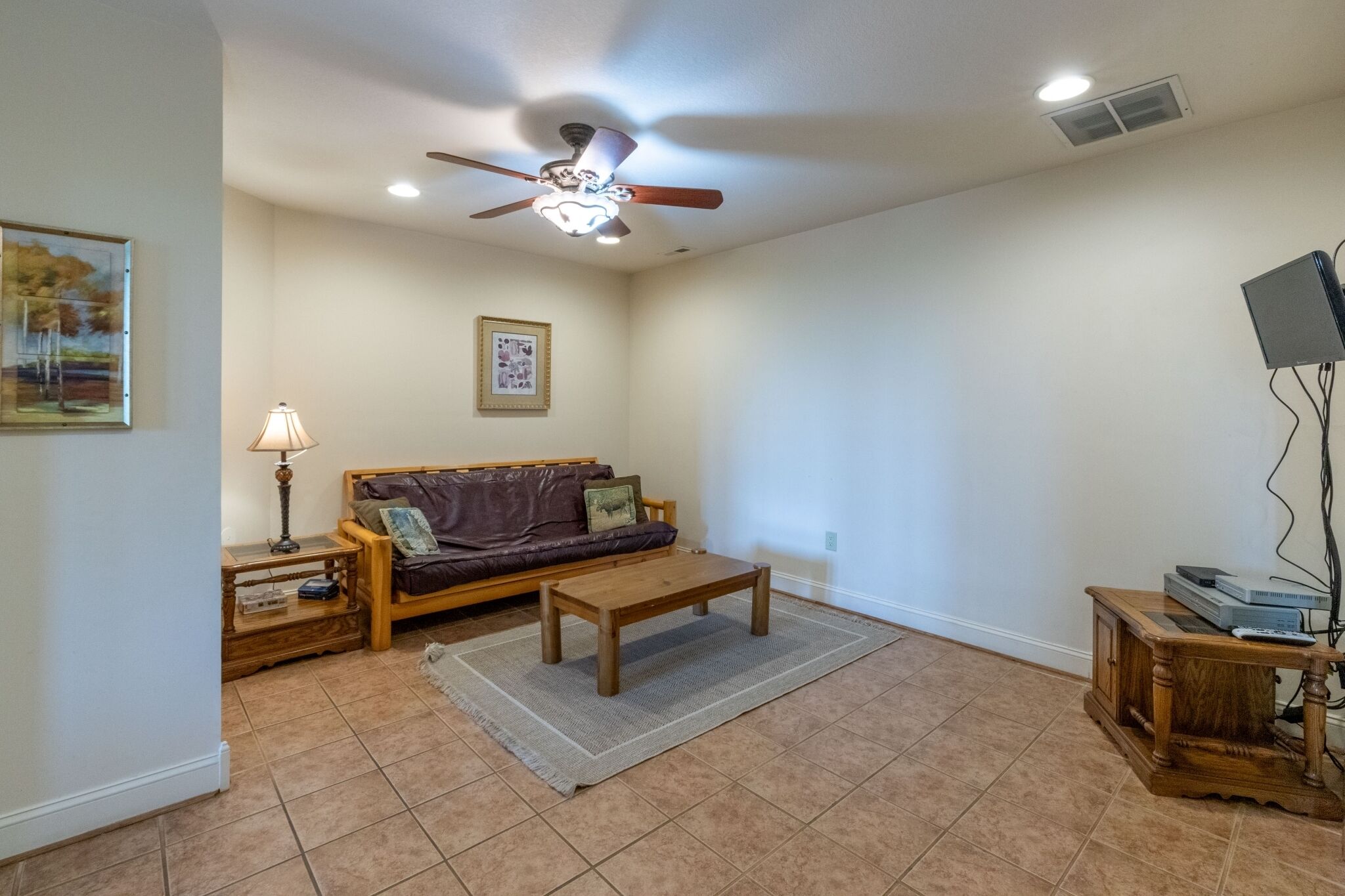 A living room with a ceiling fan, a sofa, a coffee table, a lamp, and a TV stand.