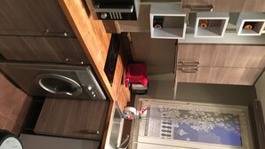 A compact kitchen with a microwave, oven, and a small refrigerator. There are wooden cabinets and a decorative window with floral patterns. - Appartement of 2 rooms, bathroom, WC and kitchen all separate, take 5 persons (Créteil)