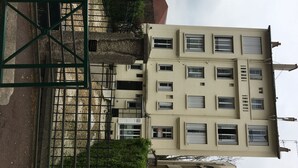 A multi-story building with a beige facade, multiple windows, and a visible air conditioning unit. - Appartement of 2 rooms, bathroom, WC and kitchen all separate, take 5 persons (Créteil)