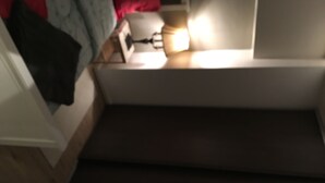 A dimly lit room with a bed, a bedside table, and a lamp. - Appartement of 2 rooms, bathroom, WC and kitchen all separate, take 5 persons (Créteil)
