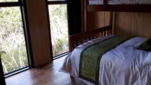 Une chambre avec un lit superposé, une grande fenêtre et une vue sur les arbres.
