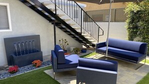 Patio esterno moderno con divani blu, una scala nera e un elemento decorativo a tema acqua.