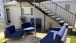 Un'area patio con due divani blu, un tavolo rotondo e una scala.