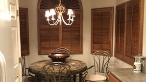 A dining area with a round table, chairs, and a chandelier.