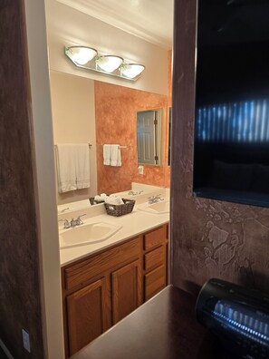 Un baño con lavamanos doble, un espejo, toallero y un aplique de pared.