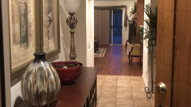 A hallway with a wooden door, a vase, and a framed picture on a cabinet.