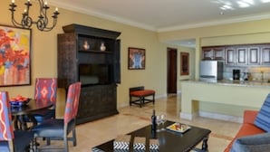 A dining area with a table, chairs, and a chandelier. There is a kitchen area with cabinets and appliances. - Ocean View Suites to Accommodate Any Party Size On the Beach (Cabo San Lucas)