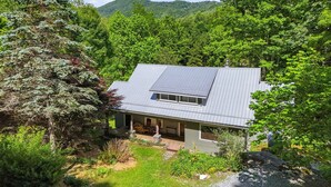 A house with a sloped roof, a covered porch, and a small front yard. - Alamo River House in Boone, NC: A charming 3BR chalet for 8 by the river! (Boone)