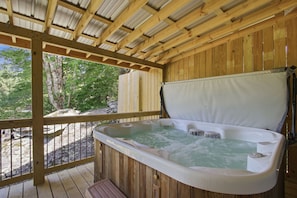 A hot tub in a wooden deck area with a view of trees.