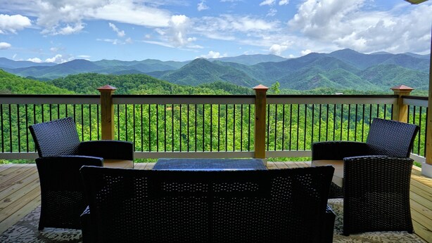 Un balcón con muebles de mimbre y vistas a montañas verdes.
