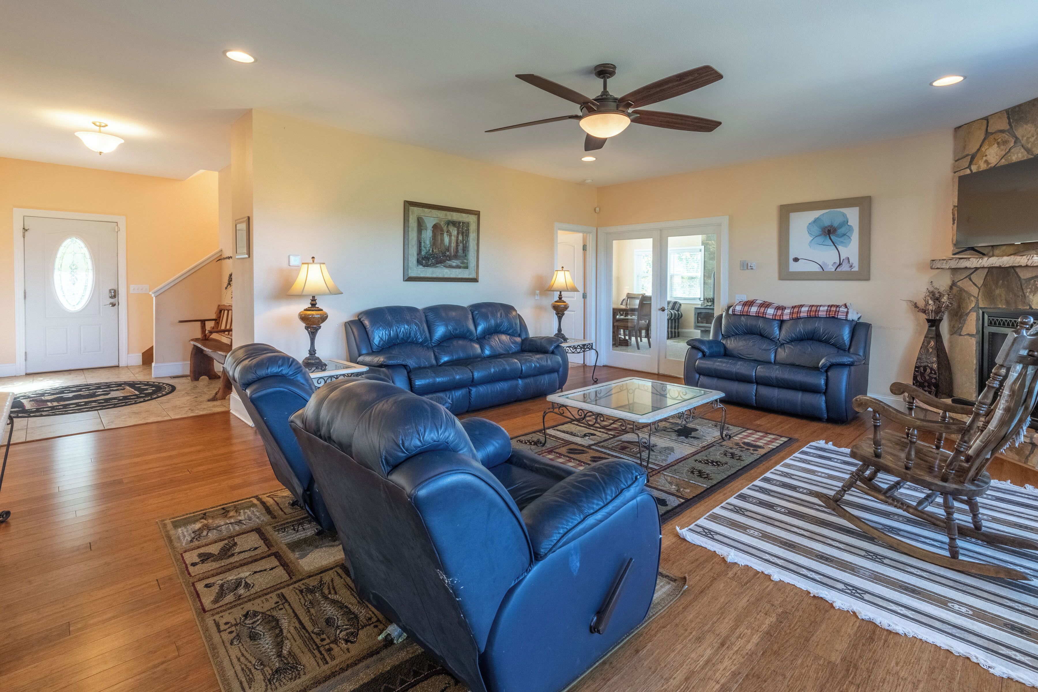 A spacious living room with leather sofas, a glass coffee table, and a fireplace.