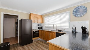 Una cocina moderna con armarios de madera, un refrigerador negro, un microondas y una tetera sobre la encimera.
