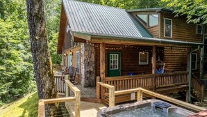 A rustic log cabin with a stone foundation, a wooden deck, and a hot tub. - Mountain Time-FW- Mountain Views - Hot Tub - Fire Pit (Bryson City)