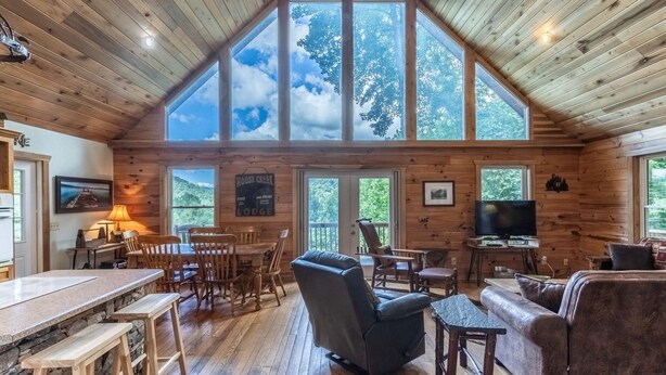 A spacious lodge with a high ceiling, large windows, a dining area, and a cozy living room. - Mountain Time-FW- Mountain Views - Hot Tub - Fire Pit (Bryson City)