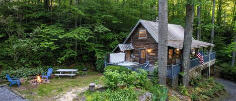A cabin with a deck, surrounded by dense forest.